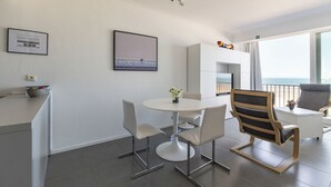 A modern living space with a dining area, a sofa, and a view of the sea. - 1 bedroom accommodation in Koksijde (Koksijde)