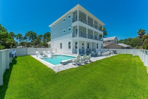 A two-story building with a pool, surrounded by a well-maintained lawn and white fences. - Beacon: 30A beaches, sleeps 26, private pool! (Santa Rosa Beach)