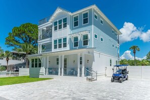 Ein zweistöckiges Strandhaus mit einer überdachten Veranda und der Hausnummer 26, die an der Fassade erkennbar ist.