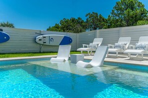A swimming pool with lounge chairs and a surfboard. - Beacon: 30A beaches, sleeps 26, private pool! (Santa Rosa Beach)