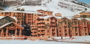 A snow-covered hotel with multiple balconies and a ski lift in the background. - Westgate 1BR ski-in/out at the Canyons Village. Pools, Hot Tubs, Ski Valet &more (Park City)