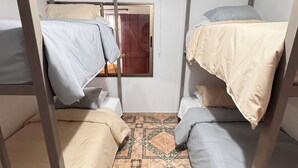 A room with bunk beds, a patterned floor, and a door with a window.