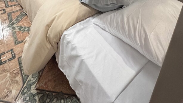 A room with a bed, a door, and a tiled floor.