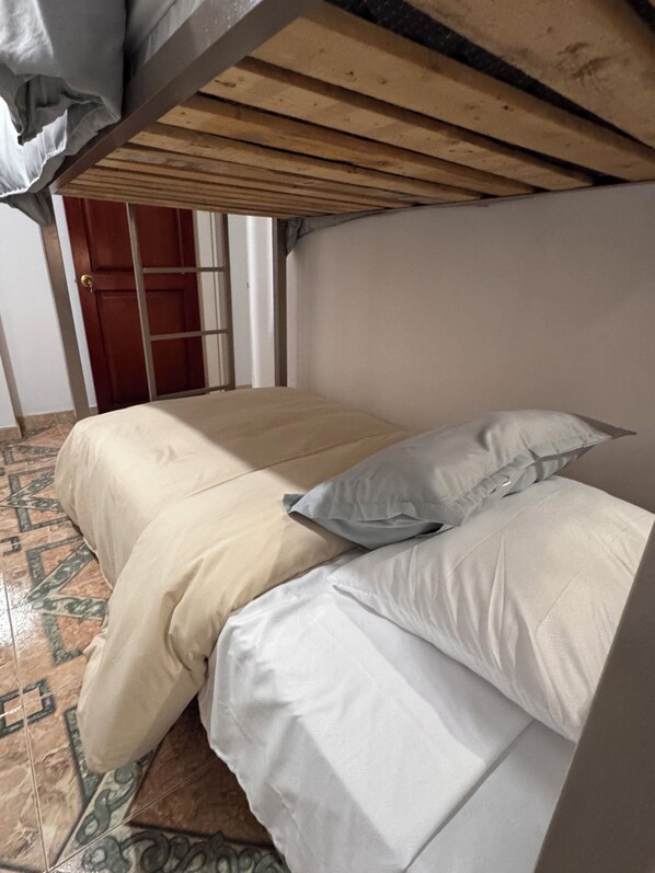 A room with a bed, a door, and a tiled floor.