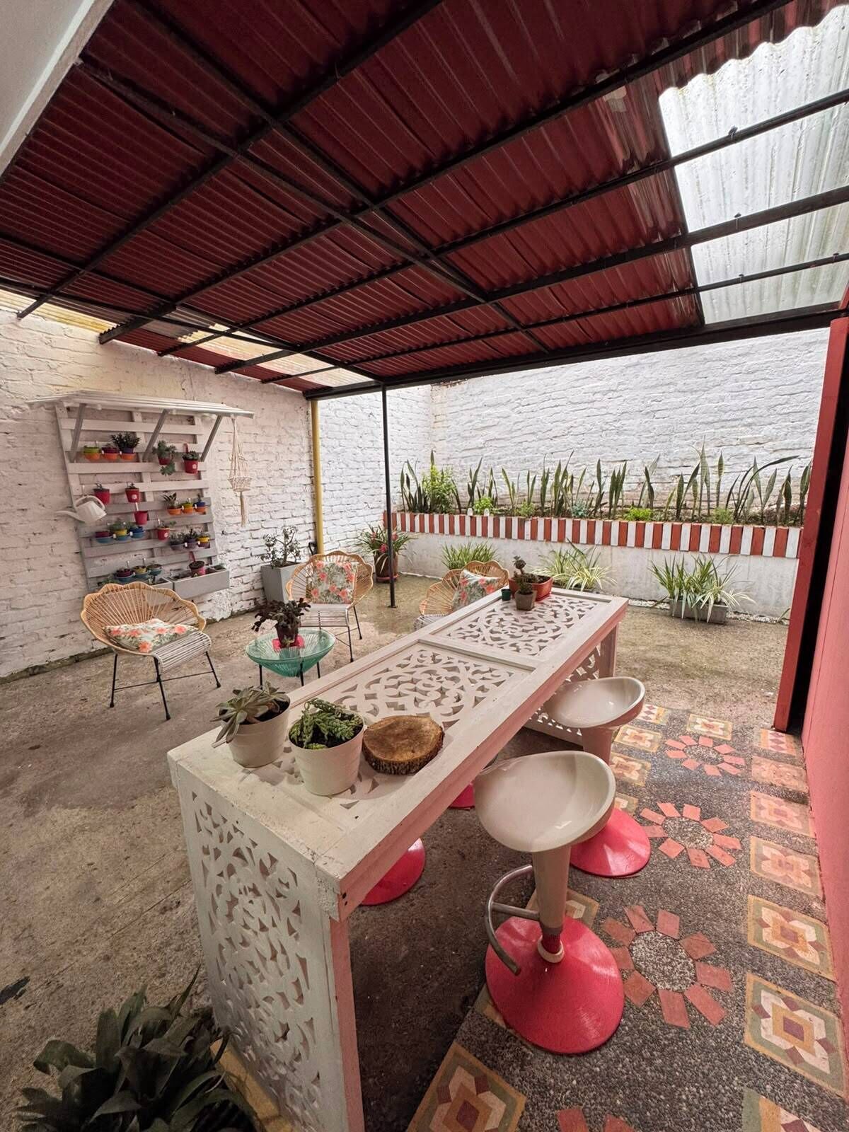 An outdoor patio with a table and chairs, potted plants, and a decorative wall.