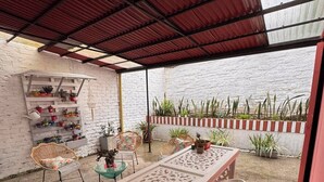 An outdoor patio with a table and chairs, potted plants, and a decorative wall.