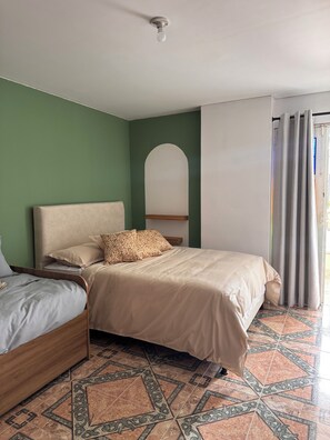 A room with a bed, a bedside table, a mirror, and a window with curtains.