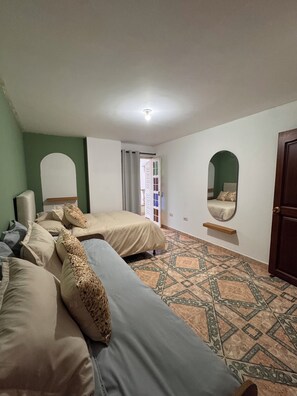A bedroom with two beds, a mirror, a door, and patterned flooring.