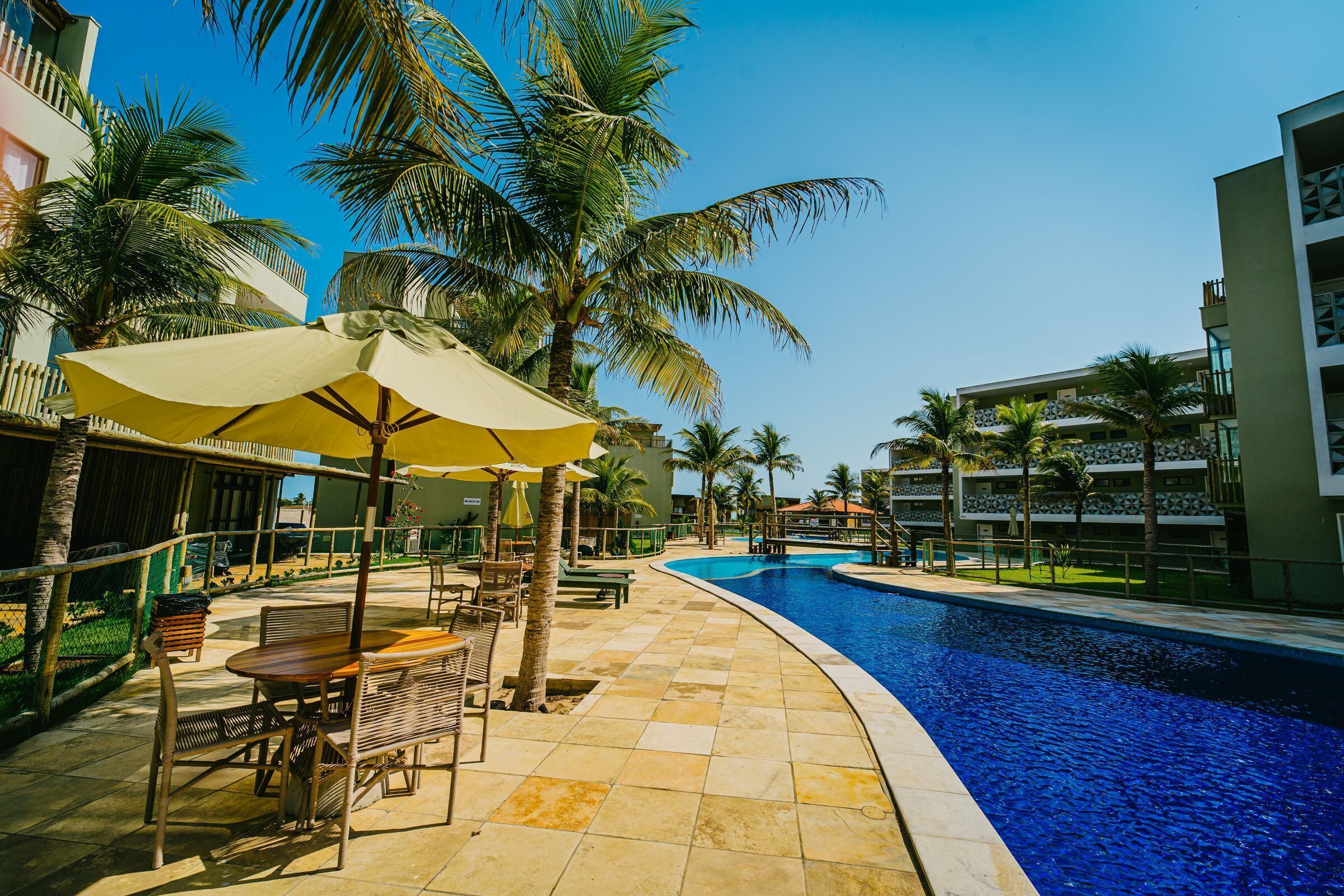 A poolside area with a tiled deck, lounge chairs, and umbrellas.