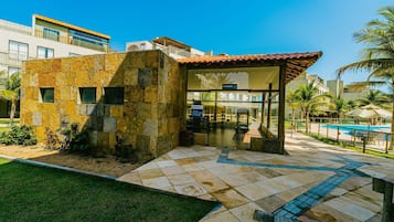 Um edifício moderno com fachada de pedra, entrada de vidro e área de piscina.