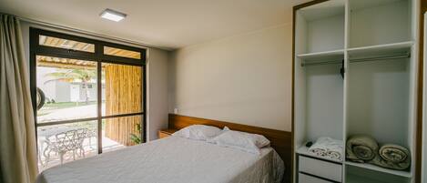 A hotel room with a bed, a wardrobe, and a window with curtains.