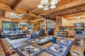 A log cabin interior with a living room, dining area, kitchen, and a staircase. - Breezy Creek Retreat-Spectacular Waterfront Cabin! (Maggie Valley)