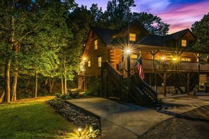 A wooden cabin with a deck, surrounded by trees. - Breezy Creek Retreat-Spectacular Waterfront Cabin! (Maggie Valley)