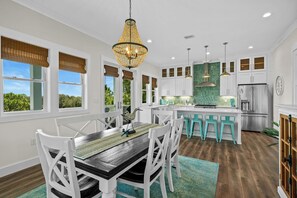 A modern kitchen with white cabinetry, a central island with bar stools, and a chandelier. - Golf Coast Cottage 4BR Beach House, Golf Views & Resort Shuttle (Gulf Shores)