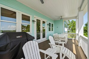 A covered porch with a table and chairs, a grill, and a view of the surrounding landscape. - Golf Coast Cottage 4BR Beach House, Golf Views & Resort Shuttle (Gulf Shores)