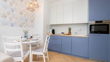Una cocina moderna con armarios blancos y azules, encimera de madera y horno empotrado.