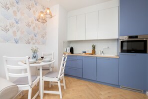 Una cocina moderna con armarios blancos y azules, encimera de madera y horno empotrado.