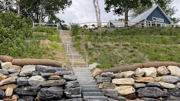 A stone staircase leading up a grassy hill with a house in the background.