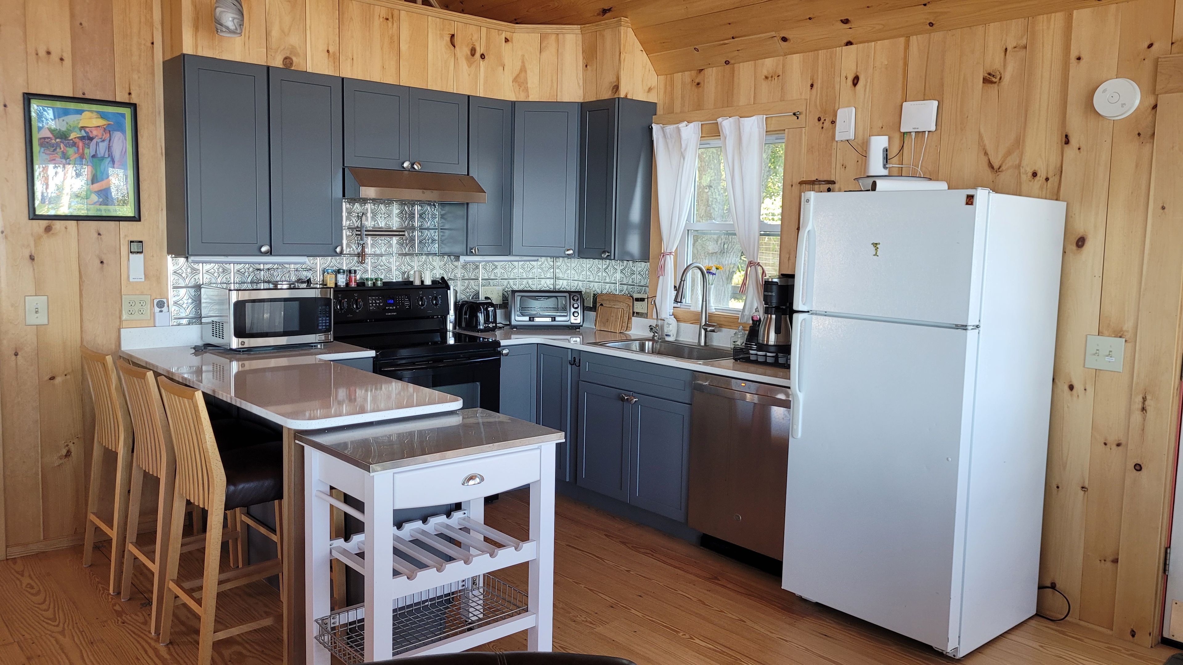 A kitchen with wooden walls, a white refrigerator, a stove, and a sink.