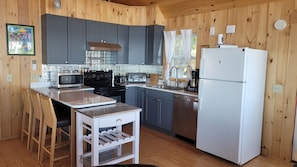 A kitchen with wooden walls, a white refrigerator, a stove, and a sink.