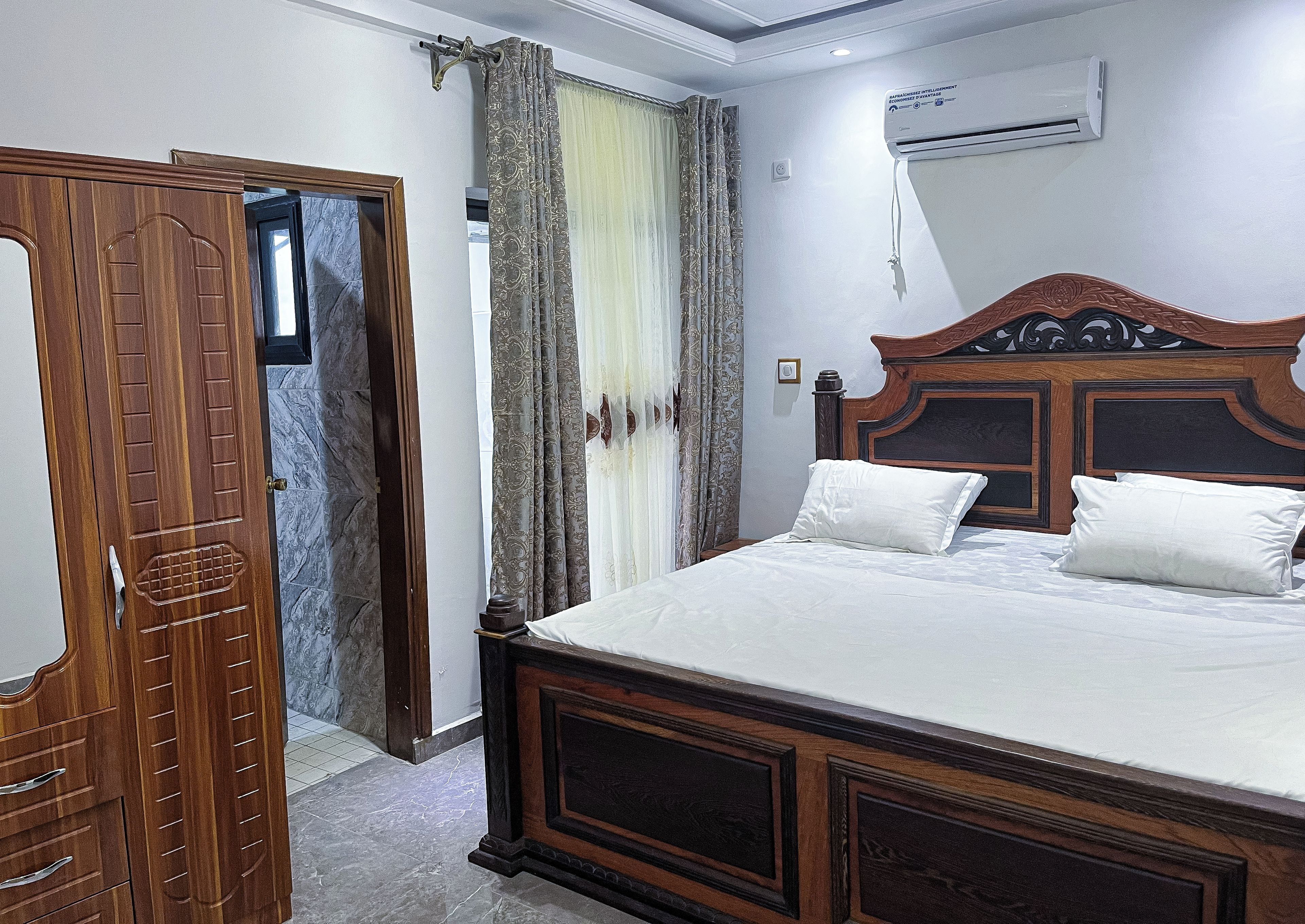 Une chambre à coucher avec un lit en bois, une armoire et un appareil de climatisation.