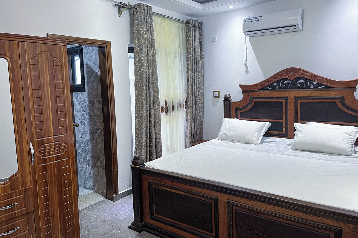 Un dormitorio con una cama de madera, un armario y un equipo de aire acondicionado.