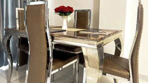 Una mesa de comedor con sillas, un florero con rosas rojas y un menú.