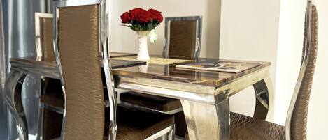 Una mesa de comedor con sillas, un florero con rosas rojas y un menú.