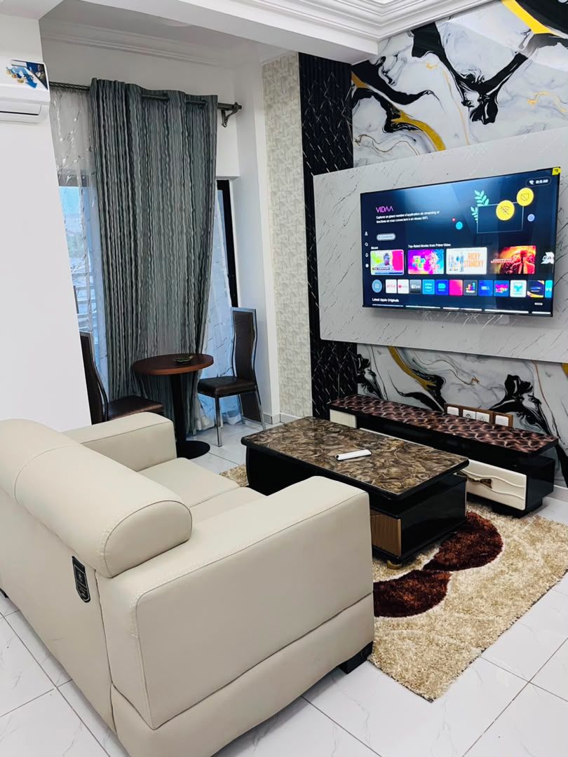 Una sala de estar moderna con un sofá, una mesa de centro y un televisor montado en la pared.