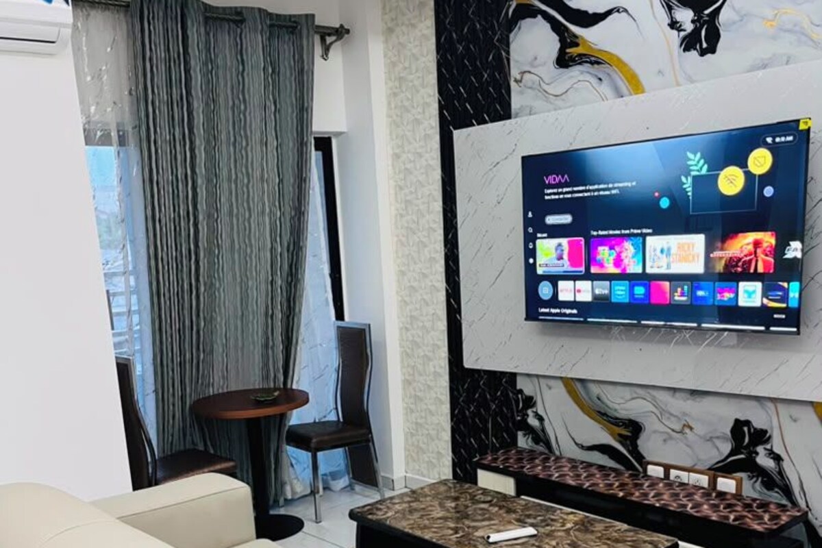 Una sala de estar moderna con un sofá, una mesa de centro y un televisor montado en la pared.