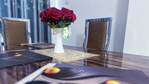 Una mesa de comedor con un florero de rosas rojas, un posavasos y otro posavasos con diseño floral.