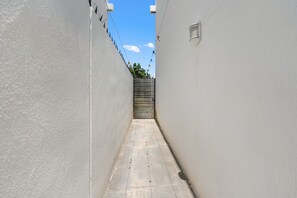 A narrow alleyway with a metal gate at the end, flanked by plain walls. - Casa Zoe Zafiro Residencial Sleeps 16 (San Vicente)