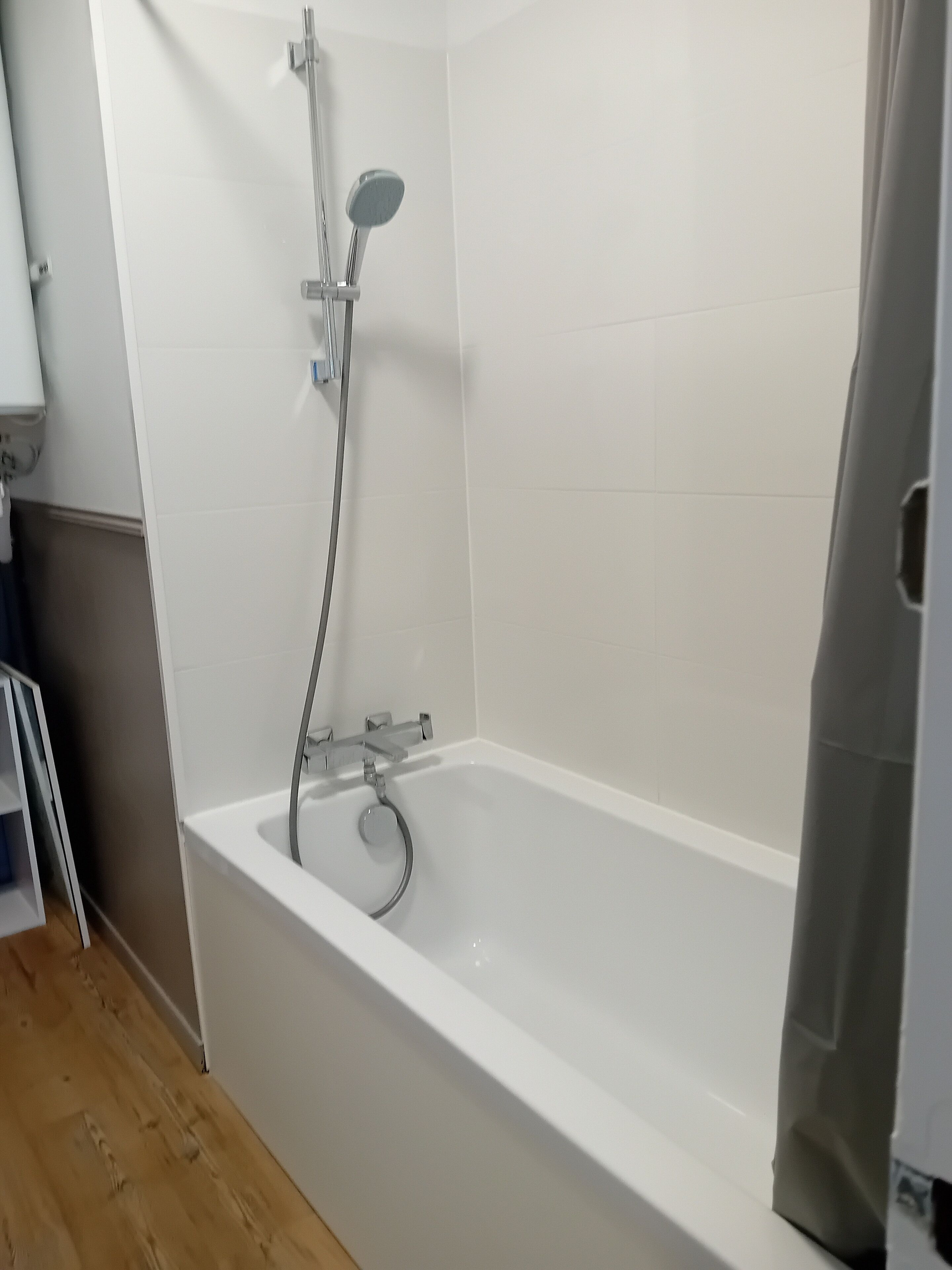 Een badkamer met een witte badkuip, een douchekop en een handdoekhouder.