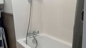 Een badkamer met een witte badkuip, een douchekop en een handdoekhouder.
