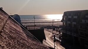 A coastal cityscape with a beach, buildings, and a clear sky.