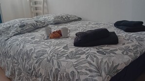 A bed with a floral-patterned bedspread, a tray with croissants and a cup, and a dark blanket on the bed.