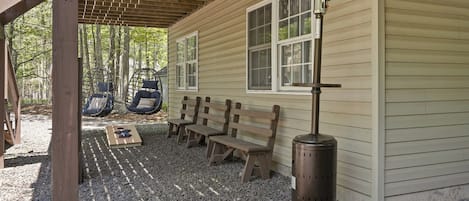 A covered outdoor seating area with benches and a wood-burning stove.