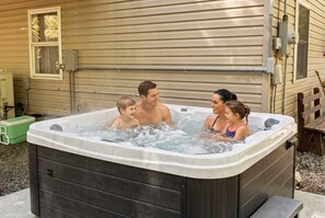 Ein Whirlpool mit vier Personen, einem grünen Kühlbox und einer Holzbank.