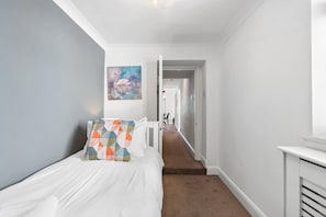 A bedroom with a bed, a painting, and a hallway leading to another room. - Seaview Haven | By My Getaways (Brighton)