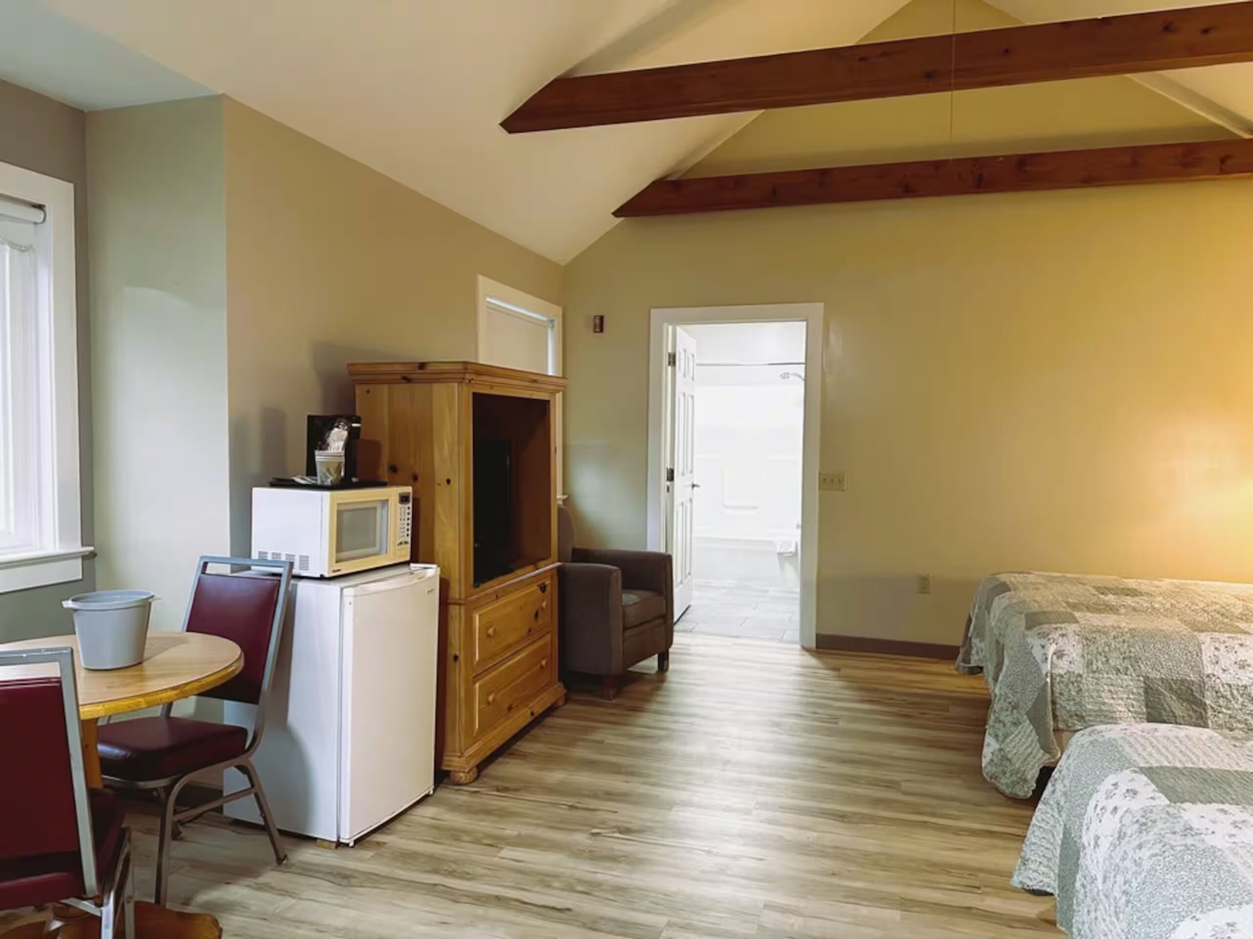 A compact room with a kitchenette, a dining area, and a bed.