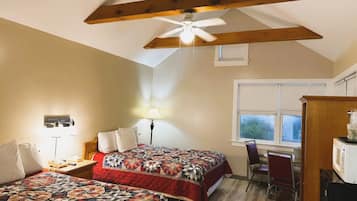 Une chambre avec deux lits, un ventilateur de plafond, un bureau avec une chaise et une fenêtre.