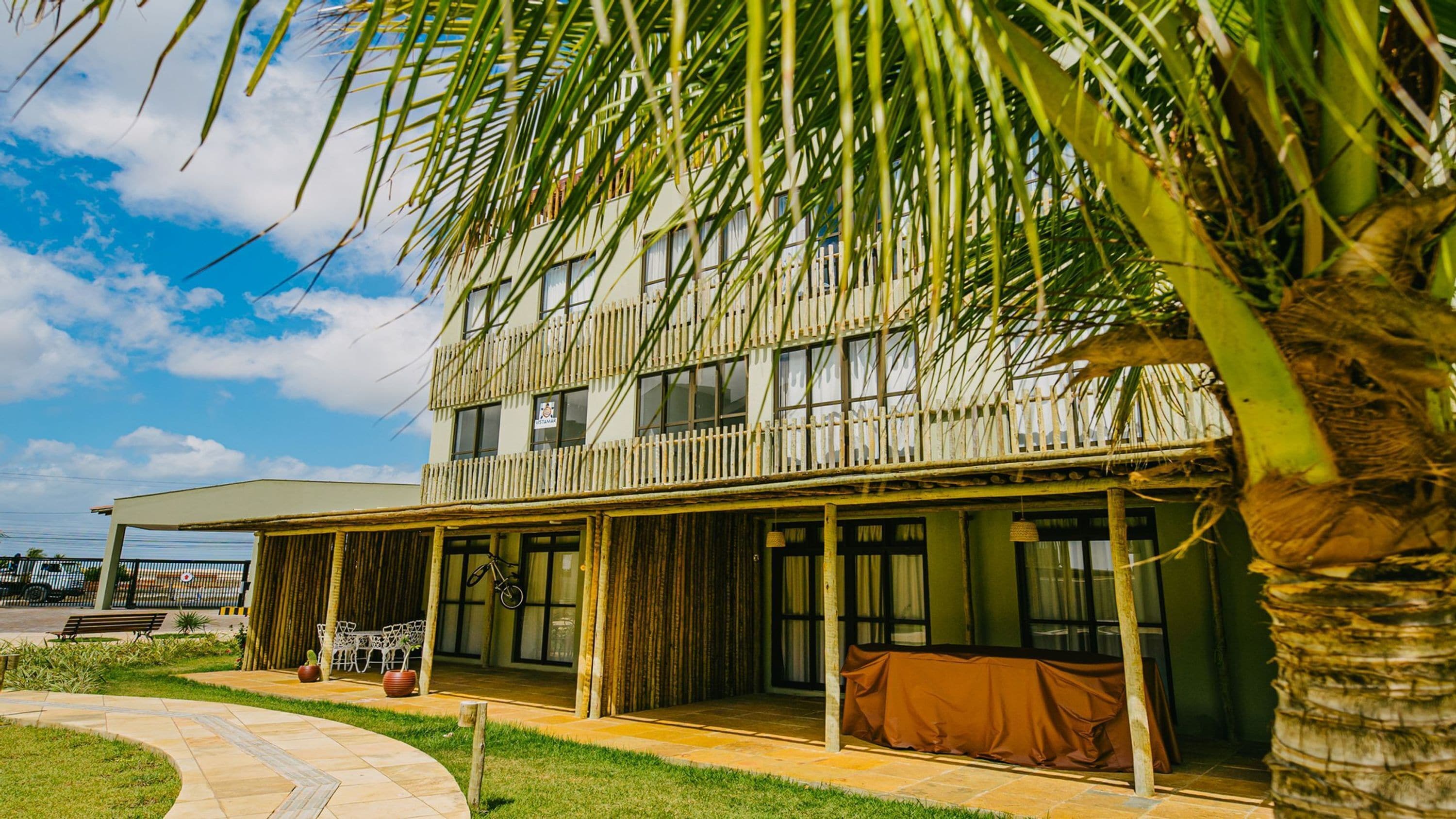 A two-story building with a covered outdoor seating area, a balcony, and a view of the sky.