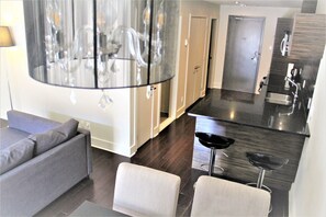 Ein modernes Wohnzimmer mit grauem Sofa, einem kleinen Tisch und einer Bar mit einem Hocker.