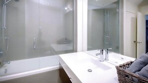A modern bathroom with a glass-enclosed shower, a white sink with two faucets, and a mirror above the sink. - MODERN CONDO IN THE HEART OF DOWNTOWN FESTIVAL DISTRICT (Montréal)