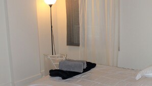 A bedroom with a bed, a bedside table, a lamp, and a window with curtains. - MODERN CONDO IN THE HEART OF DOWNTOWN FESTIVAL DISTRICT (Montréal)