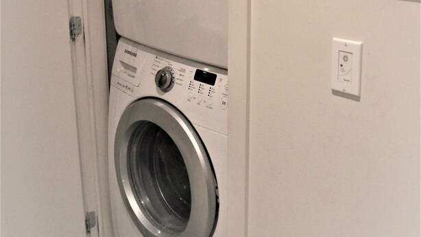 A stacked washer and dryer unit in a room with a door leading to another area. - MODERN CONDO IN THE HEART OF DOWNTOWN FESTIVAL DISTRICT (Montréal)