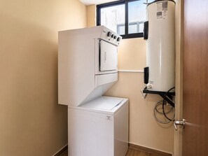 A compact laundry room with a washer and dryer, a water heater, and a window. - En el corazón de marina Mazatlán (Mazatlán)