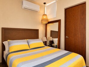 A hotel room with a bed, an air conditioning unit, a wooden door, and a mirror. - En el corazón de marina Mazatlán (Mazatlán)