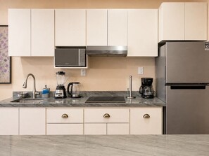 Een moderne keuken met een roestvrijstalen koelkast, een ingebouwde magnetron en een koffiezetapparaat.