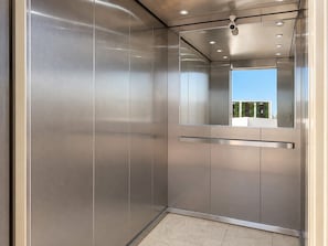 A modern elevator with metallic walls and a reflective surface. - En el corazón de marina Mazatlán (Mazatlán)